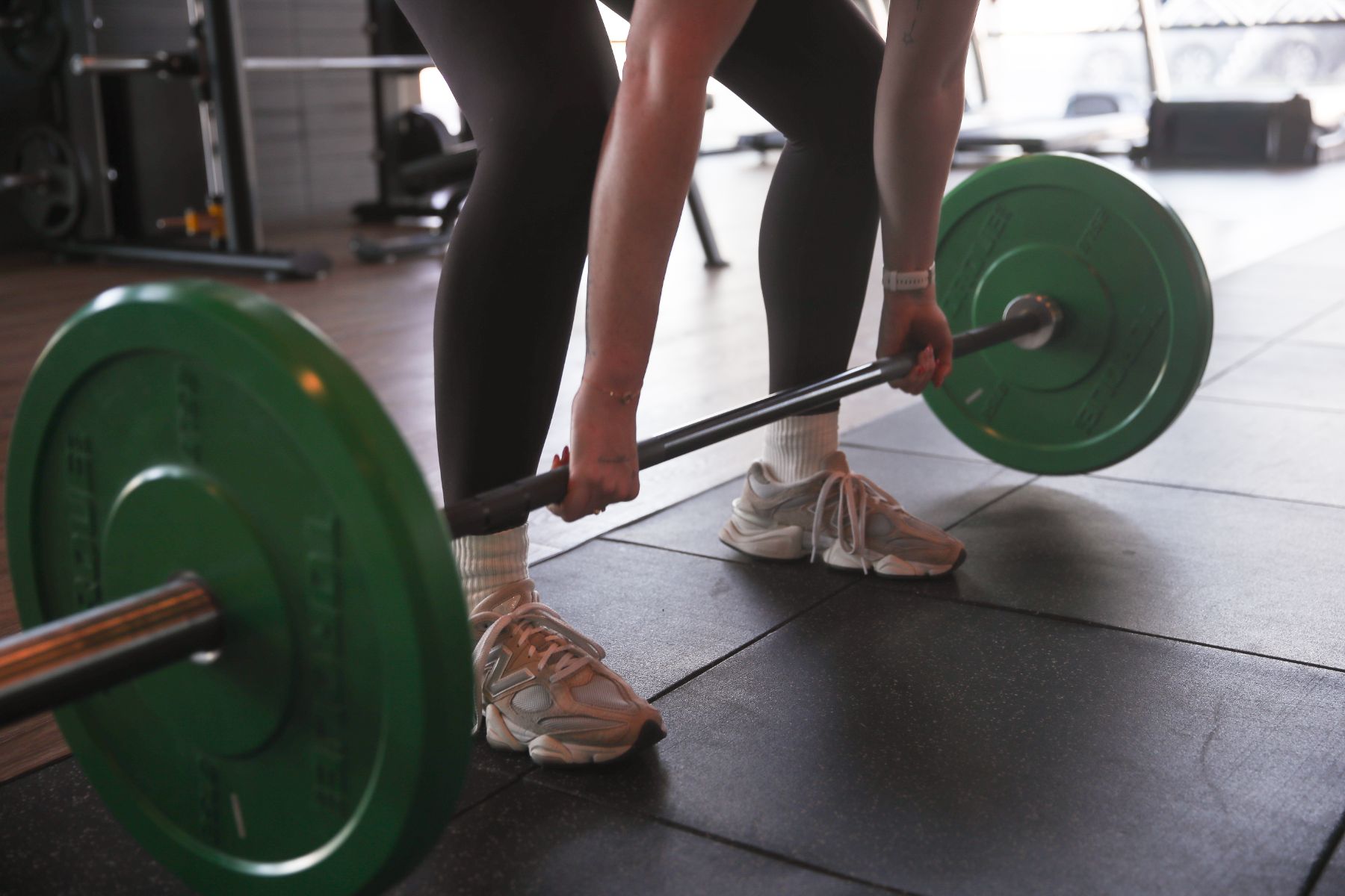 The coach deadlifts a barbell loaded with weight plates.